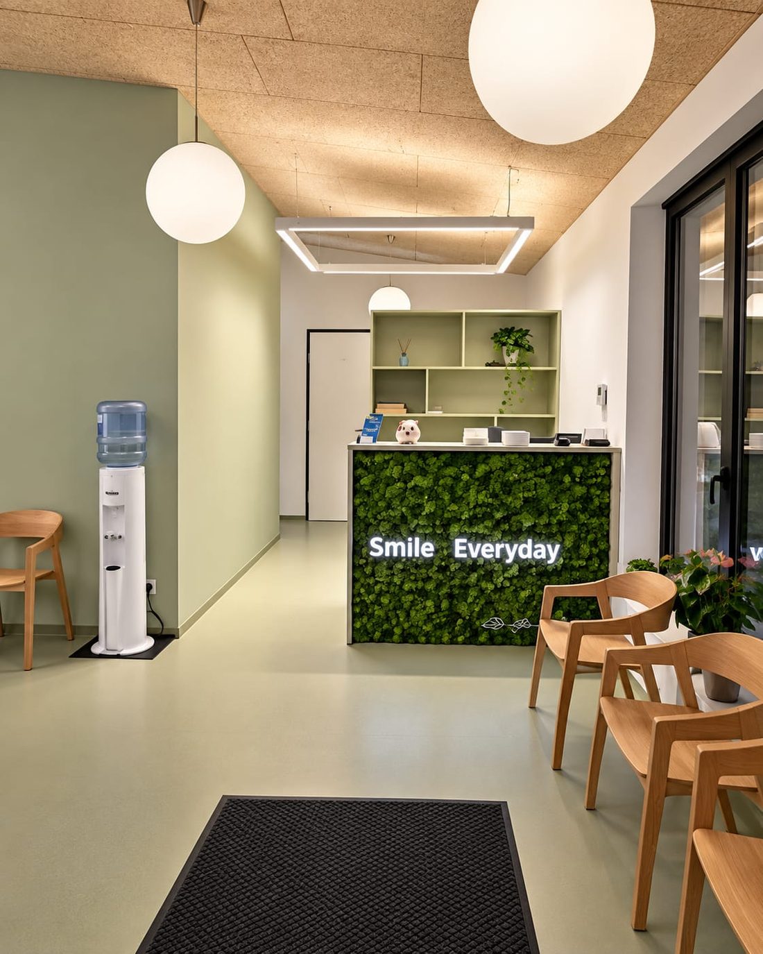 Empfang der Zahnarztordination Payerbach mit begrüntem Rezeptionspult und beleuchtetem Schriftzug „Smile Everyday“
