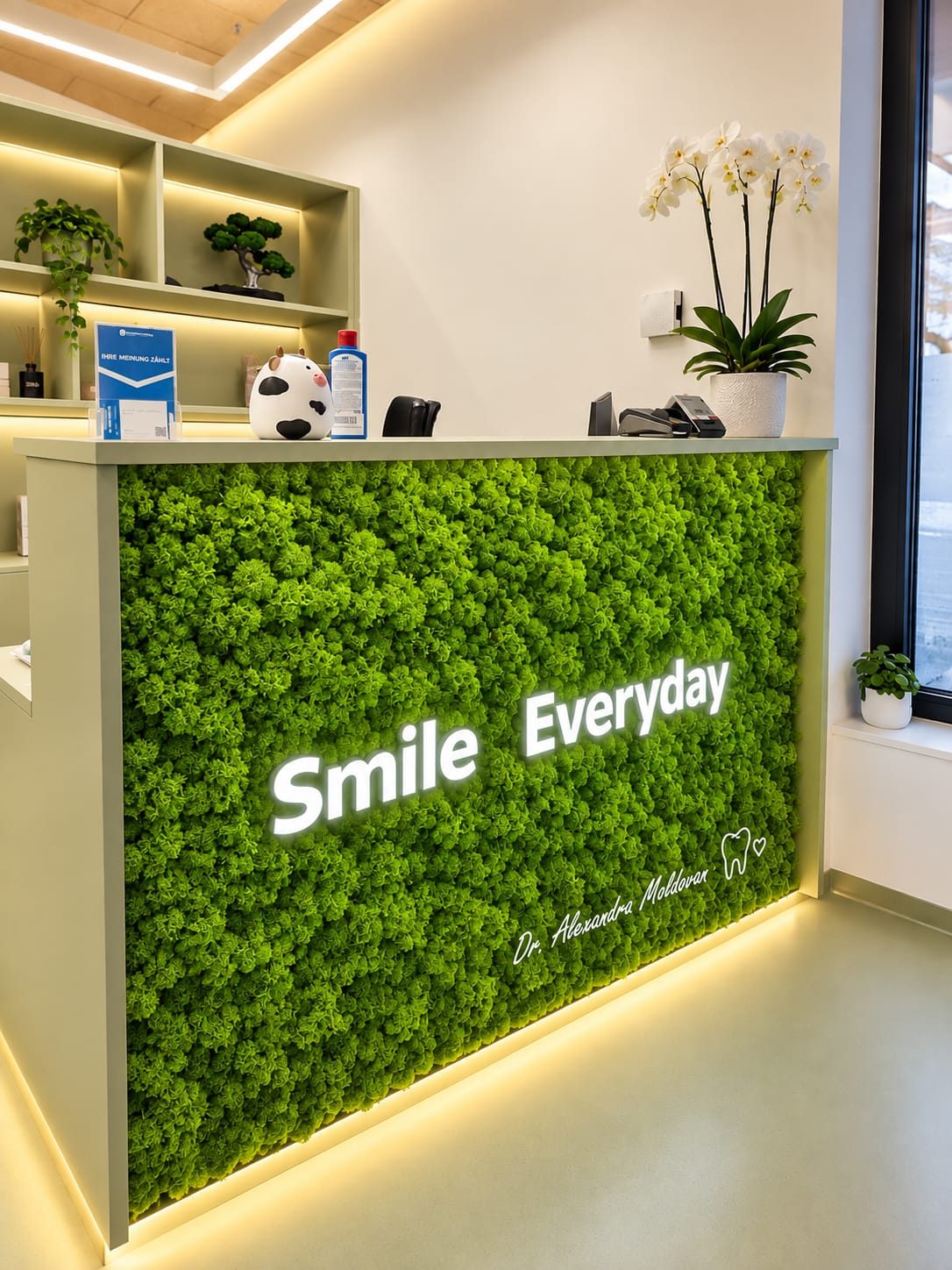 Rezeptionspult mit Mooswand, Schriftzug „Smile Everyday“ und Signatur von Dr. Moldovan