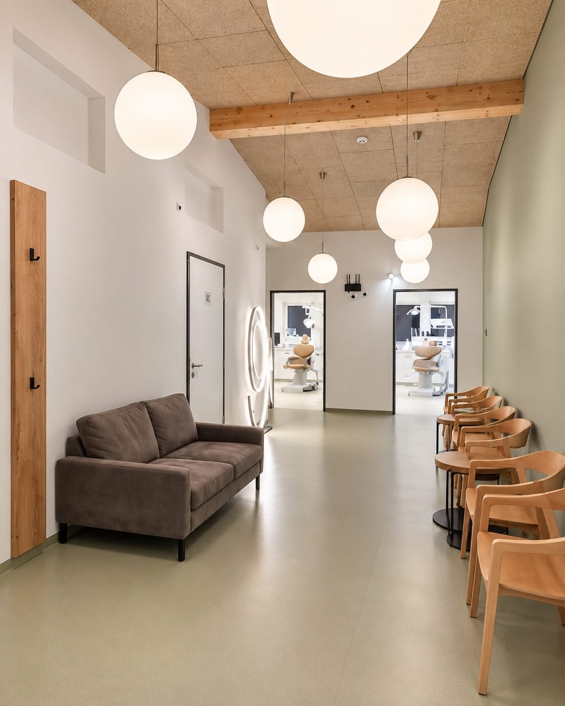 Wartebereich mit Sofa, Garderobe und Kugelleuchten in der Zahnarztordination Payerbach